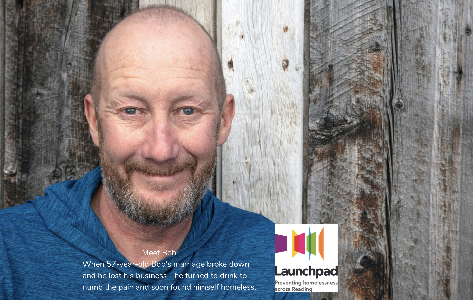 A middle-aged man with a shaved head and short beard smiles slightly, standing in front of a weathered wooden wall. Launchpad charity logo is in the bottom right corner. Text describes his story.