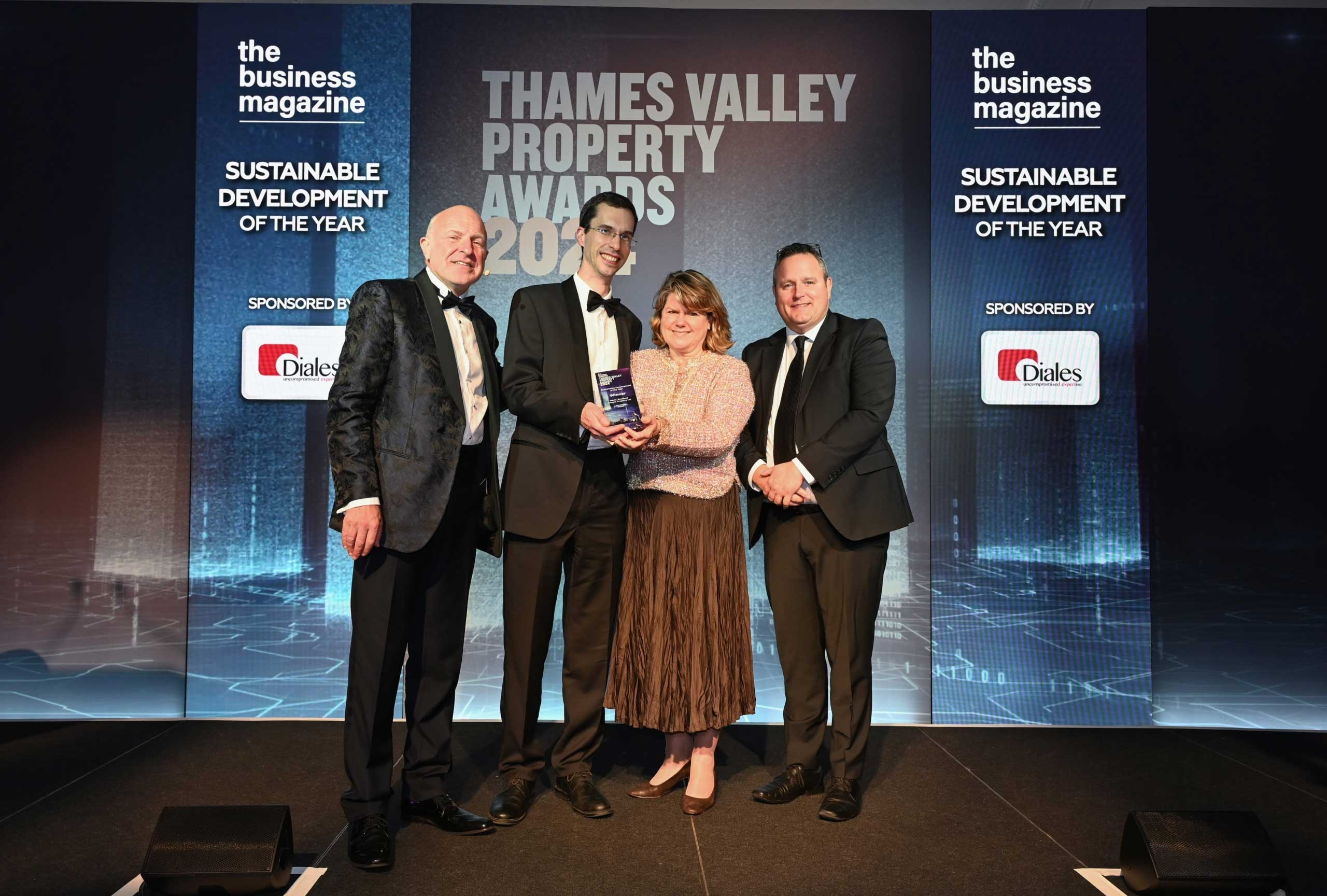 Four people stand on stage holding an award at the Thames Valley Property Awards 2023, with event sponsor logos displayed on each side.